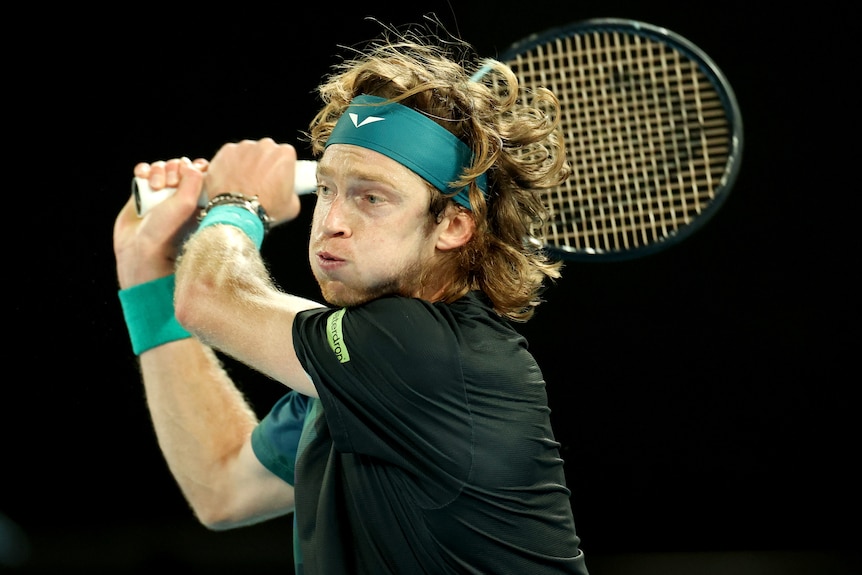Andrey Rublev hits a double-fisted backhand at the 2024 Australian Open.