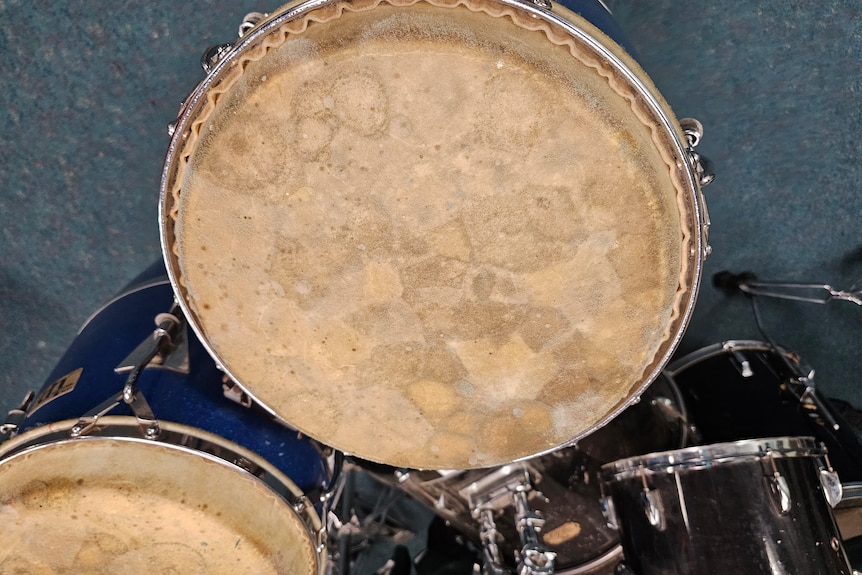 A drum kit with mould growing over it.