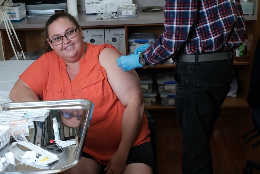 Directorul Pitcairn, Charlene Warren, stă să primească un vaccin COVID de la un medic de sex masculin. 