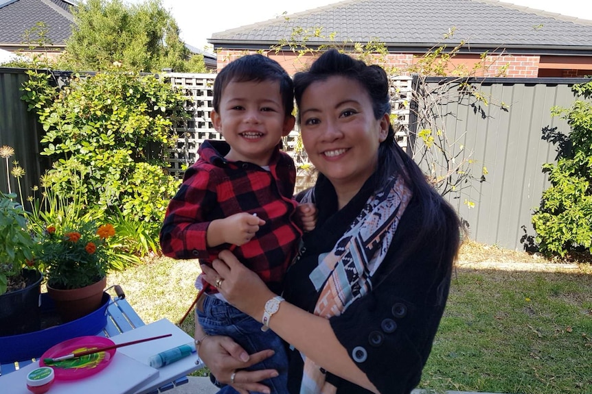 Khin Cameron holding her son Harvey in the backyard of the Merna home.