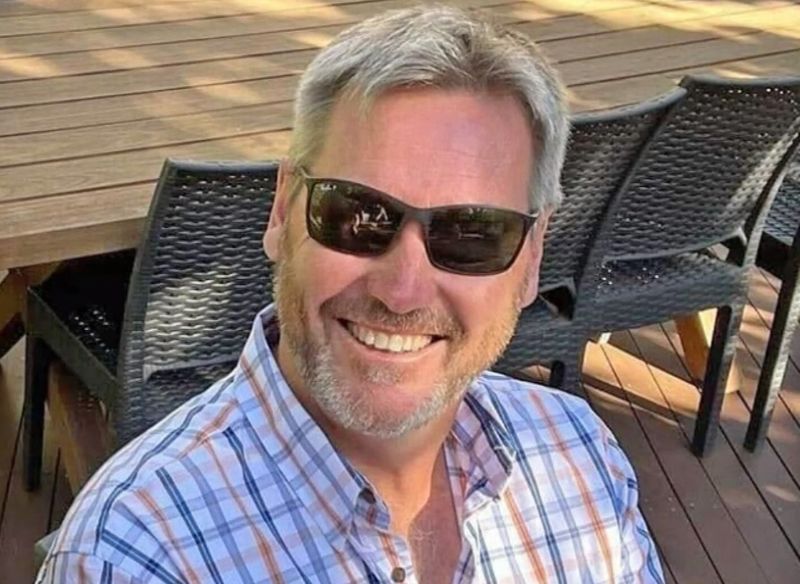 A man wears checkered shirt and black sunglasses