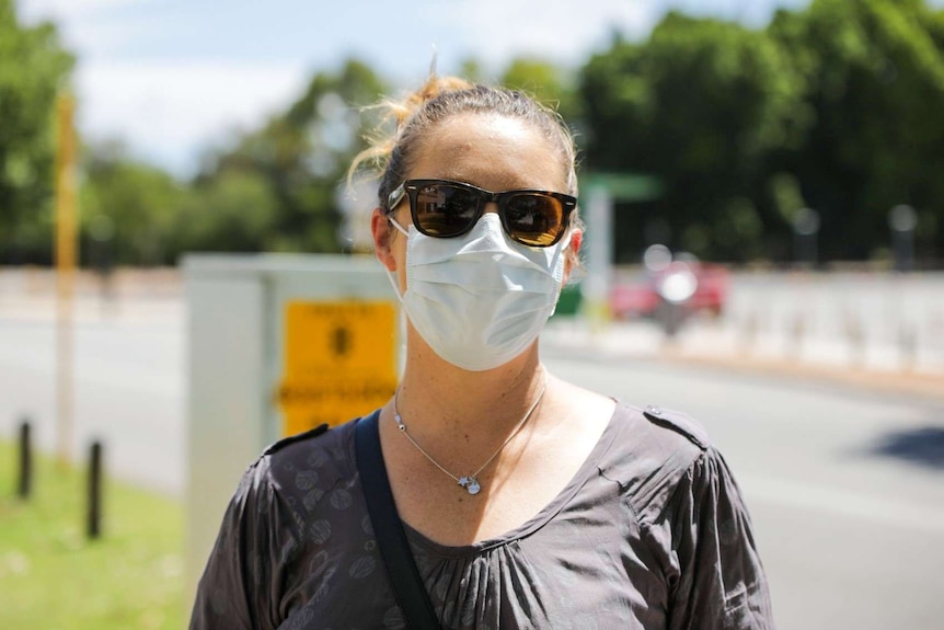 Ms Keenan wears a mask and stands in front of a road.