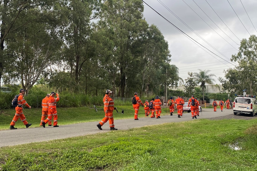 People in orange uniforms walking down a road