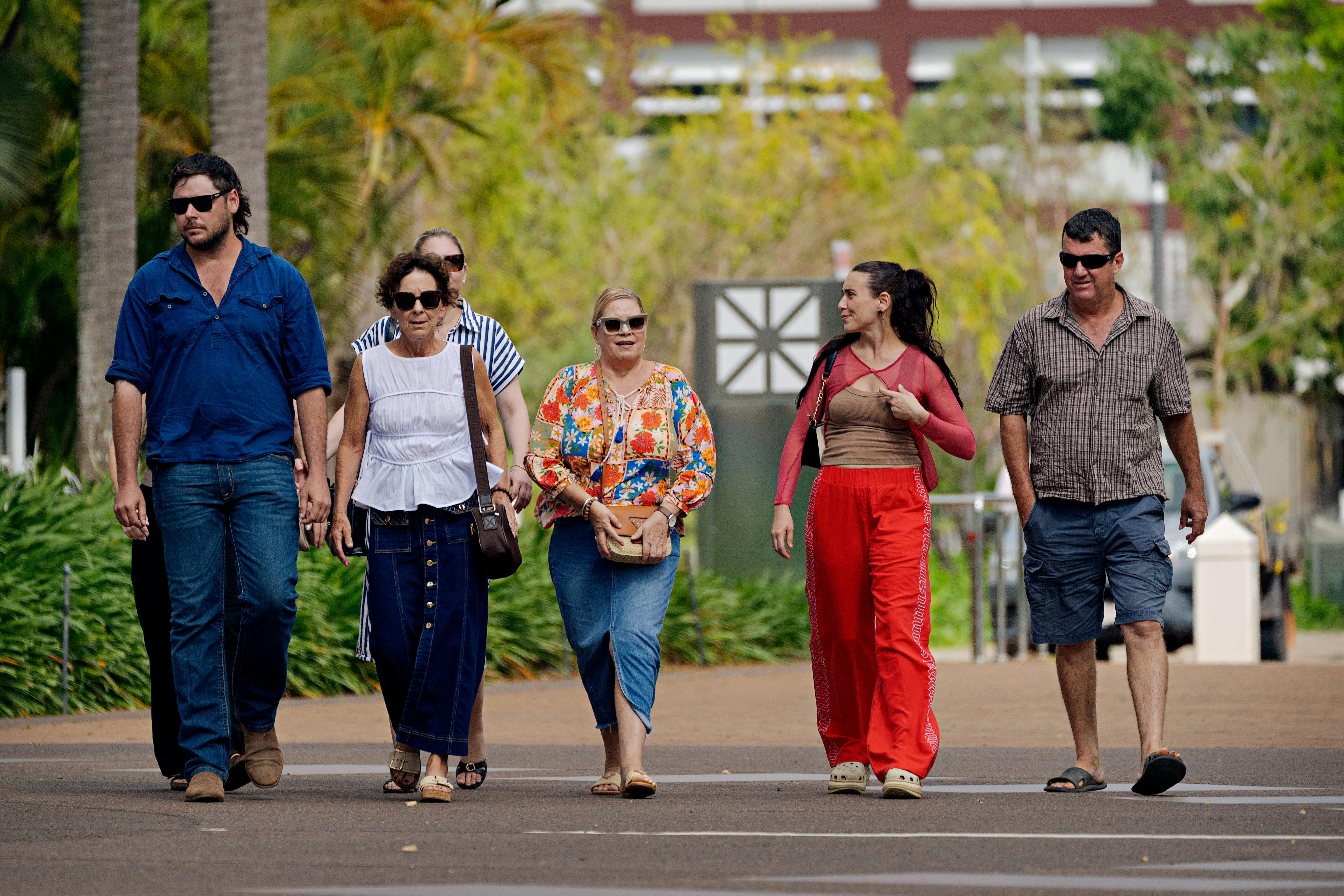 Un grupo de cinco personas caminan juntas por un sendero y se miran con expresiones serias.