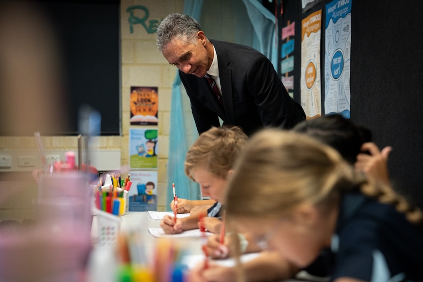 WA Education Minister Tony Buti standing behind school children at their desks in a primary school classroom