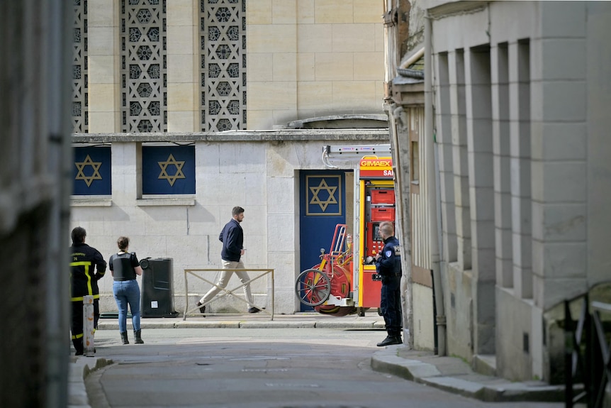 A zoomed-in view down an alleyway shows four men standing in front of a building marked with blue and yellow Stars of David.