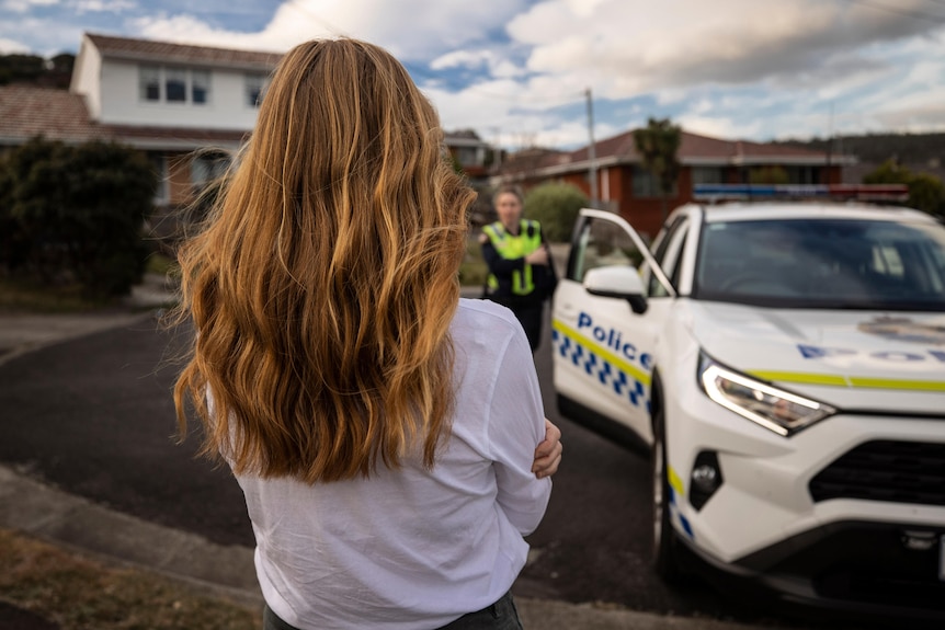 An unidentified woman watches the police approach from a police car.