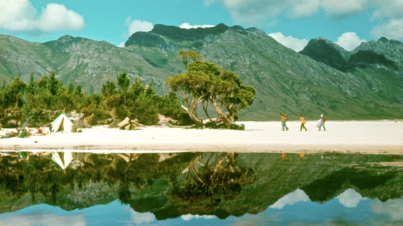 Old photograph with saturated colours of pink quartz beach at Lake Pedder and mountains reflected in lake