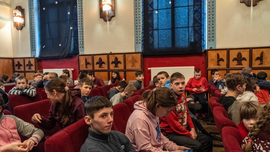 A group of children sit in pews 