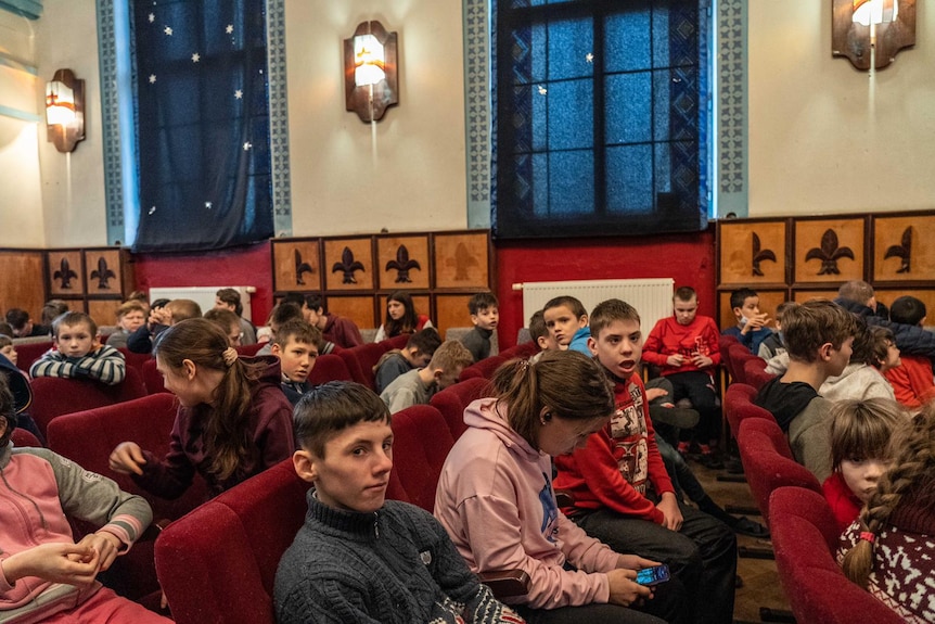 A group of children sit in pews 