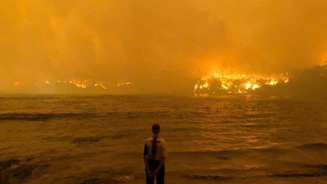 A man watches on at a golden blaze over the ocean