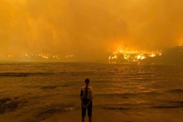 A man watches on at a golden blaze over the ocean