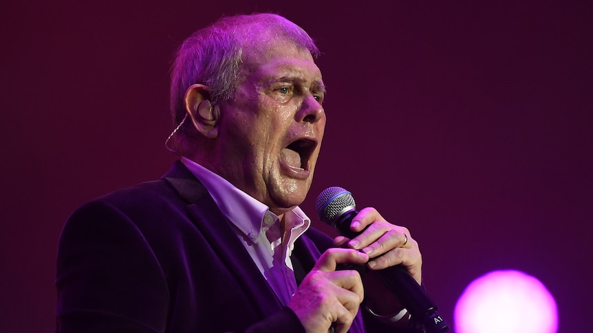 John Farnham singing into a microphone. 