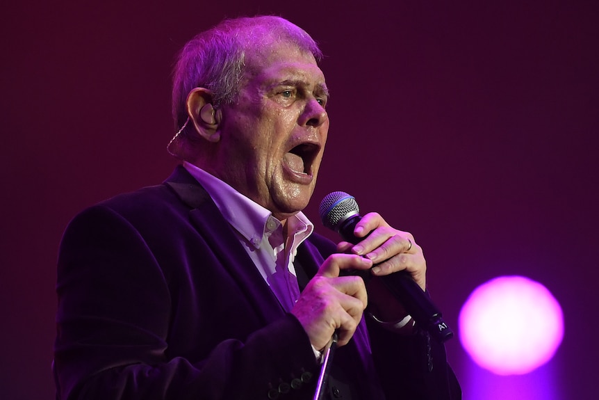 John Farnham singing into a microphone. 