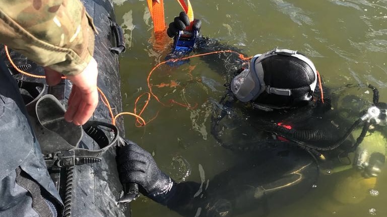 A Royal Navy diver prepares to inspect a submerged World War II bomb in the Thames.