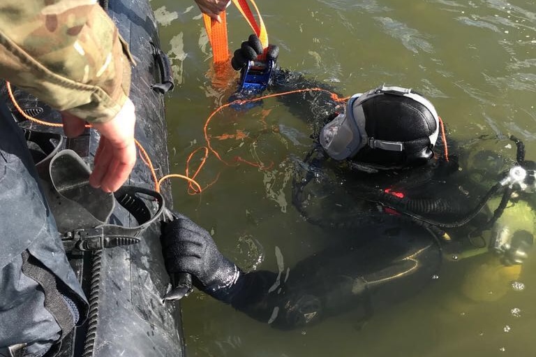 A Royal Navy diver prepares to inspect a submerged World War II bomb at London City Airport.
