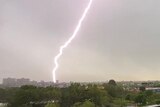 A photo of a lightening strike on a building taken from a balcony.
