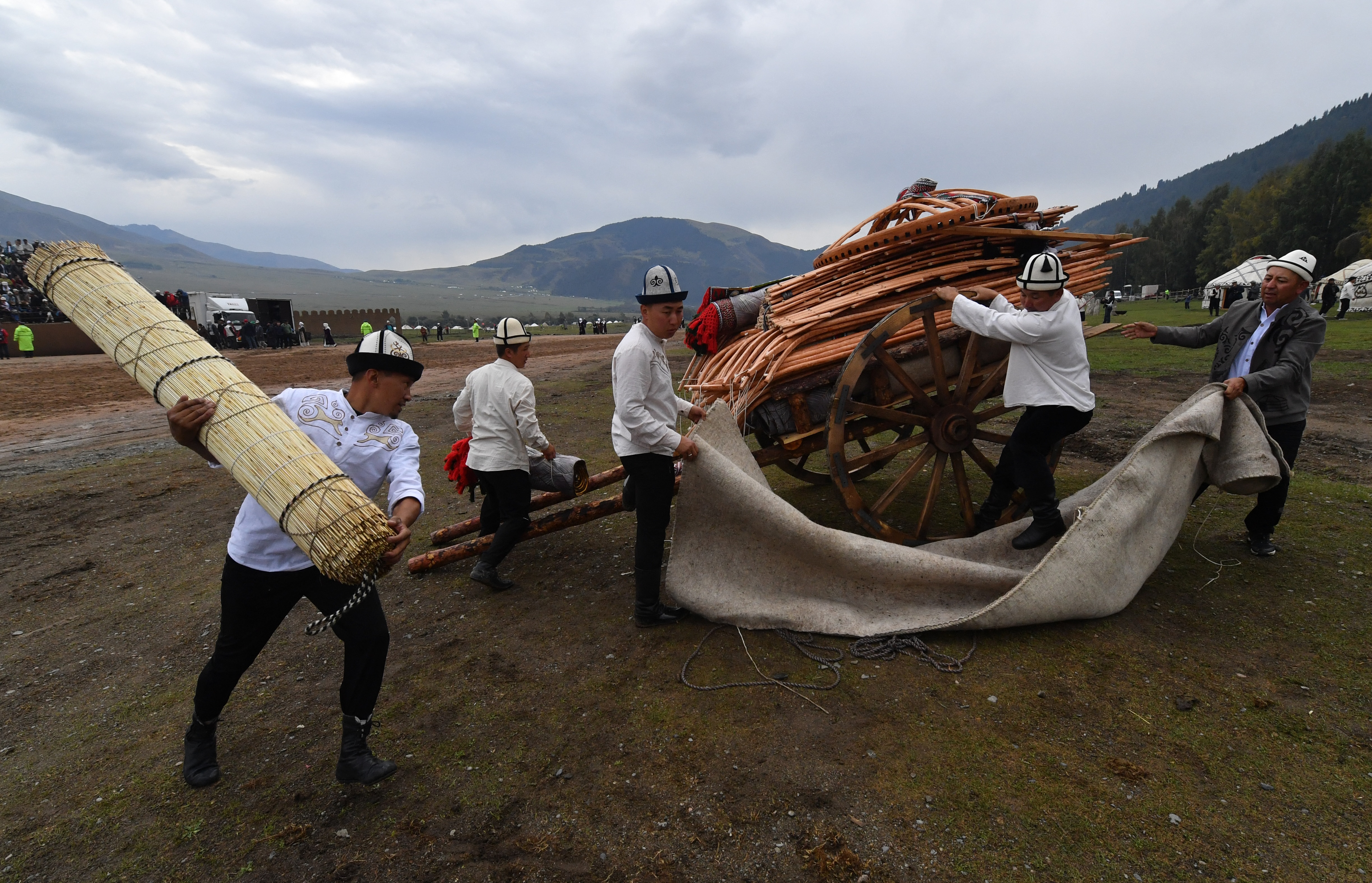 people carry parts of a yurt.
