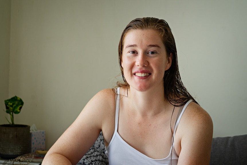 A woman smiles at the camera inside a room.