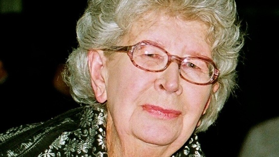 A close up photo of Coral Bell, a woman with silver hair in red framed spectacles