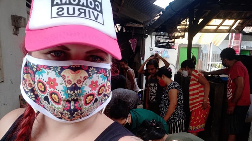 A woman wearing a hat and a face mask taking a selfie