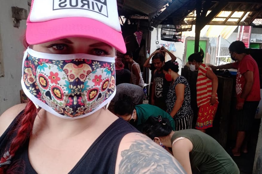 A woman wearing a hat and a face mask taking a selfie