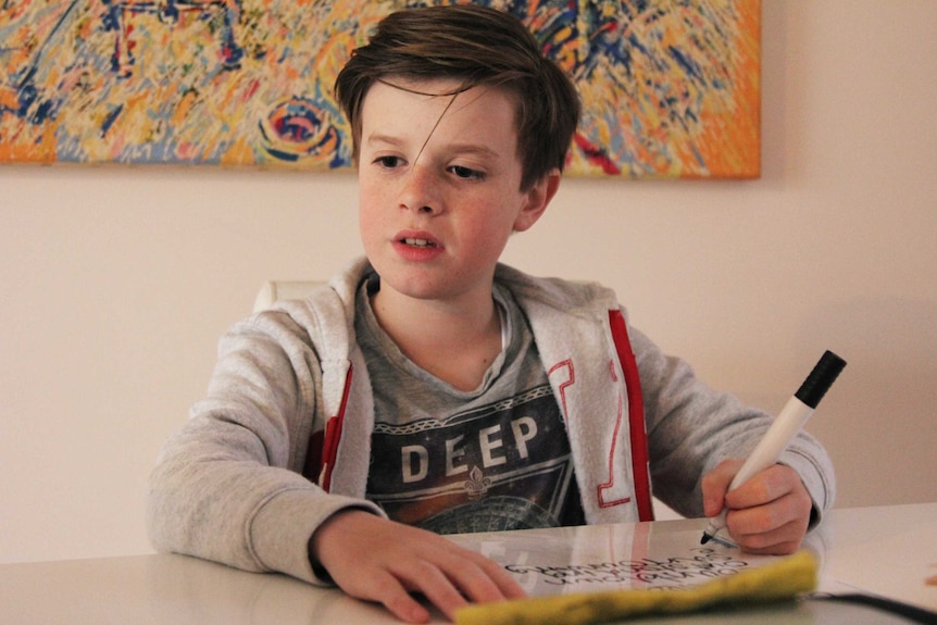 A young boy writes with a marker pen.