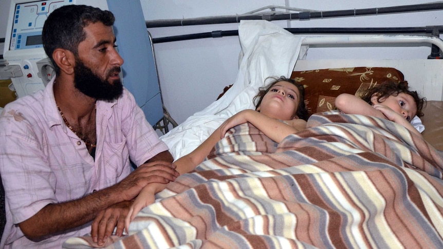 Man sits with two bedridden girls