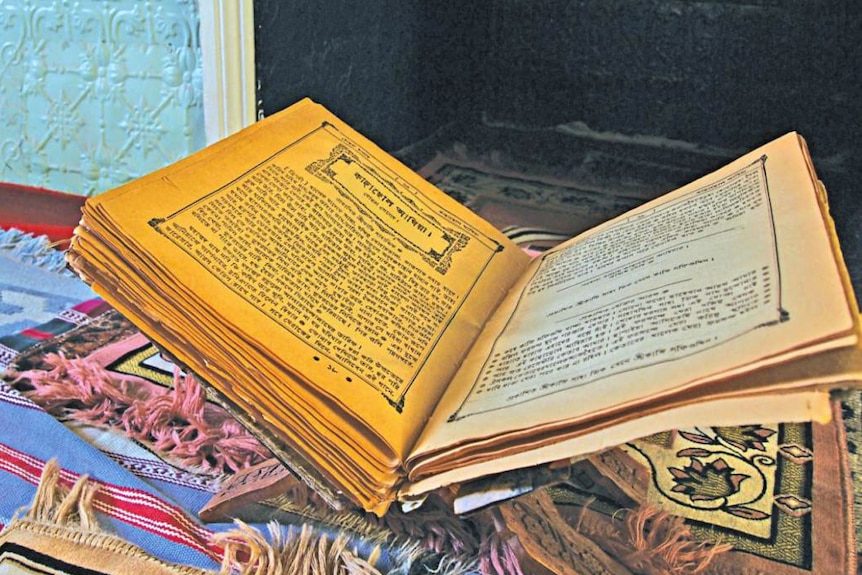 A book stands open in front of a pressed tin wall