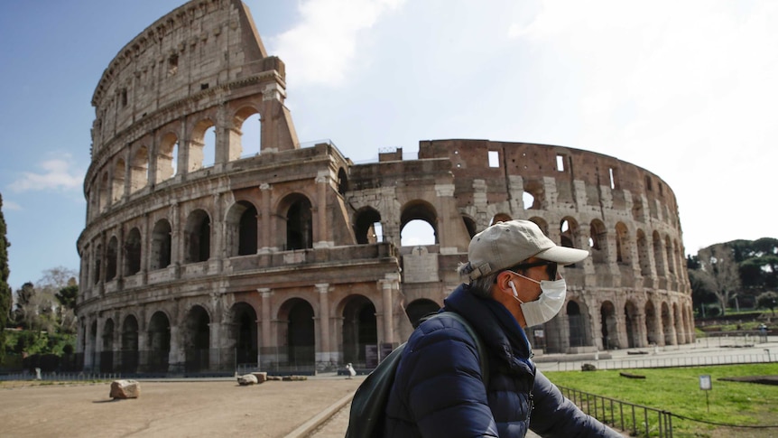 A man wearing a mask rides past an empty Colosseum in Rome