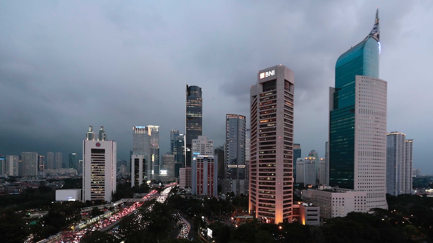 Grey skies behind Jakarta's skyline, with a congested road running into the distance.
