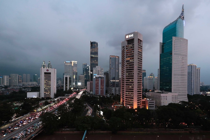 Grey skies behind Jakarta's skyline, with a congested road running into the distance.