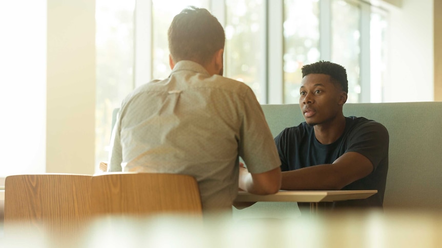 Two men talk at a table for a story on when someone can be dismissed from a job.