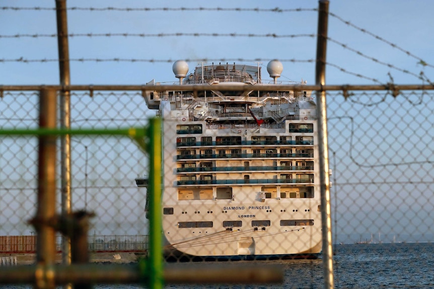 The quarantined Diamond Princess cruise ship sits behind a barbed wire fence.