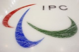 Three agito symbols, coloured blue, red and green, can be seen on ice with the letters 'IPC' above them. 