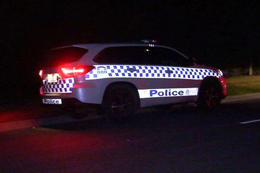 A police car parked on the side of the road in the dark.