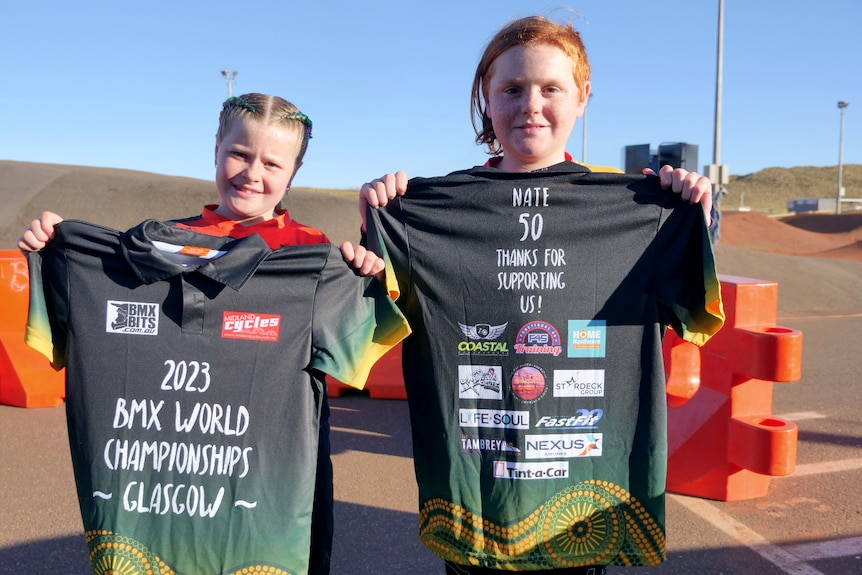 Two smiling children holding up T-shirts