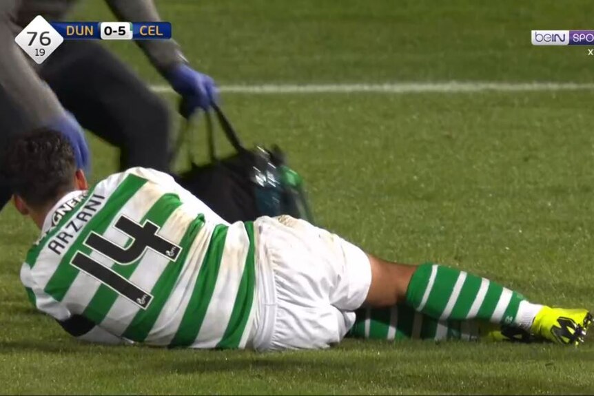 Daniel Arzani writhes in pain after injuring his knee in a game for Celtic against Dundee.