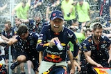 Sergio Perez and the Red Bull team run during celebrations as champagne is sprayed