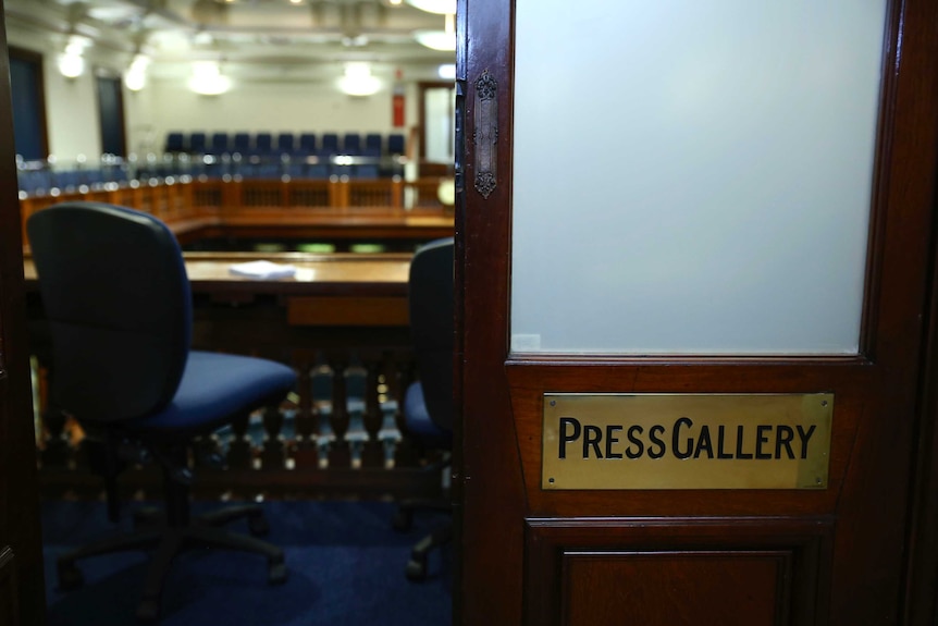 A close-up of the door to the WA Parliament Legislative Assembly press gallery with one side open and chairs inside.