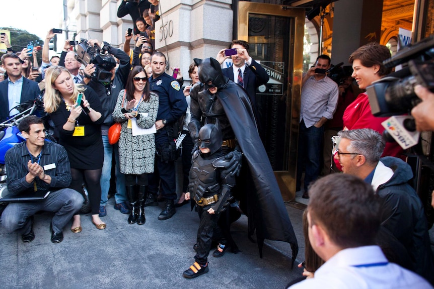 BatKid and Batman leave a former bank after arresting the Riddler