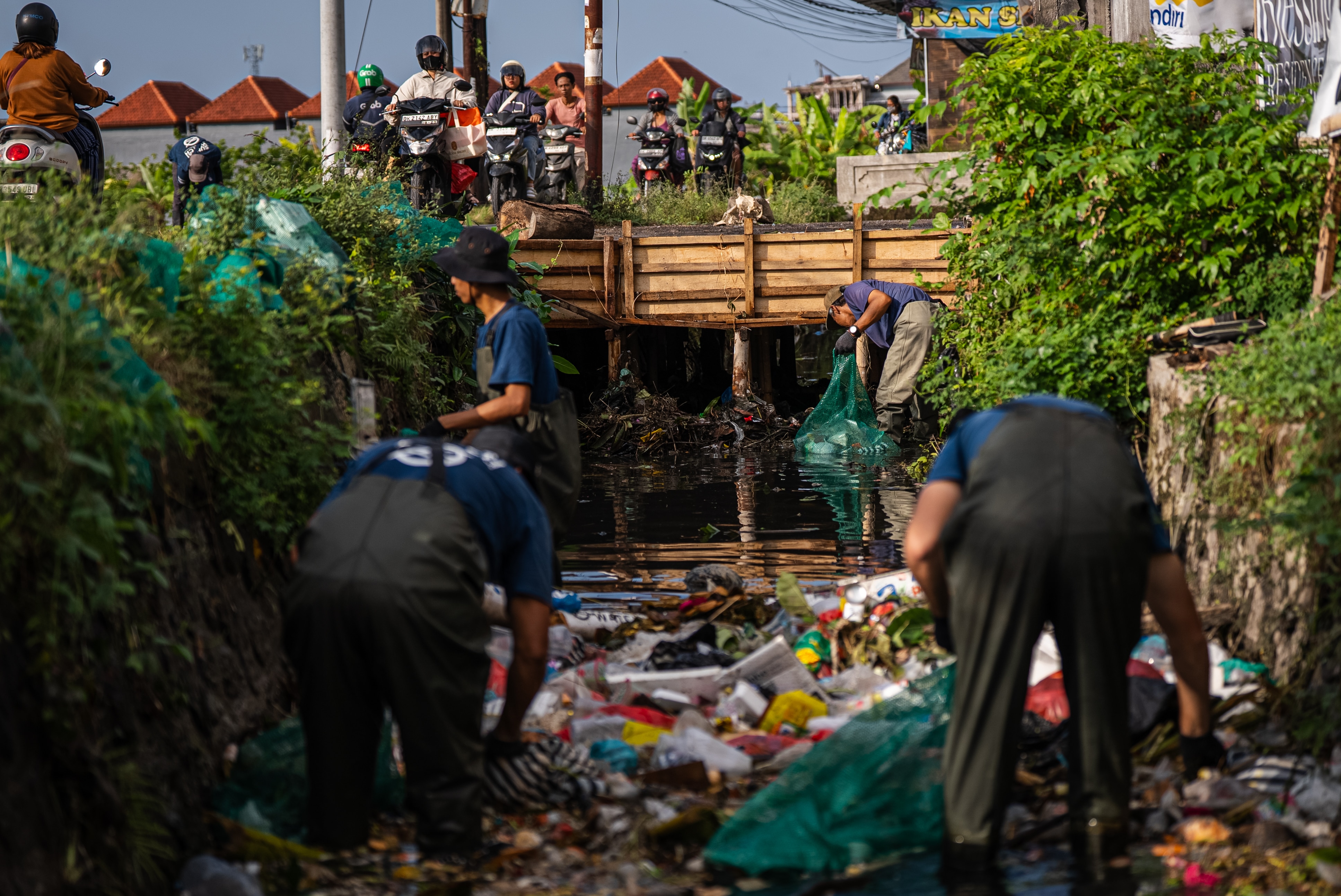 A group of volunteers clean up a river filled with trash in Bali.