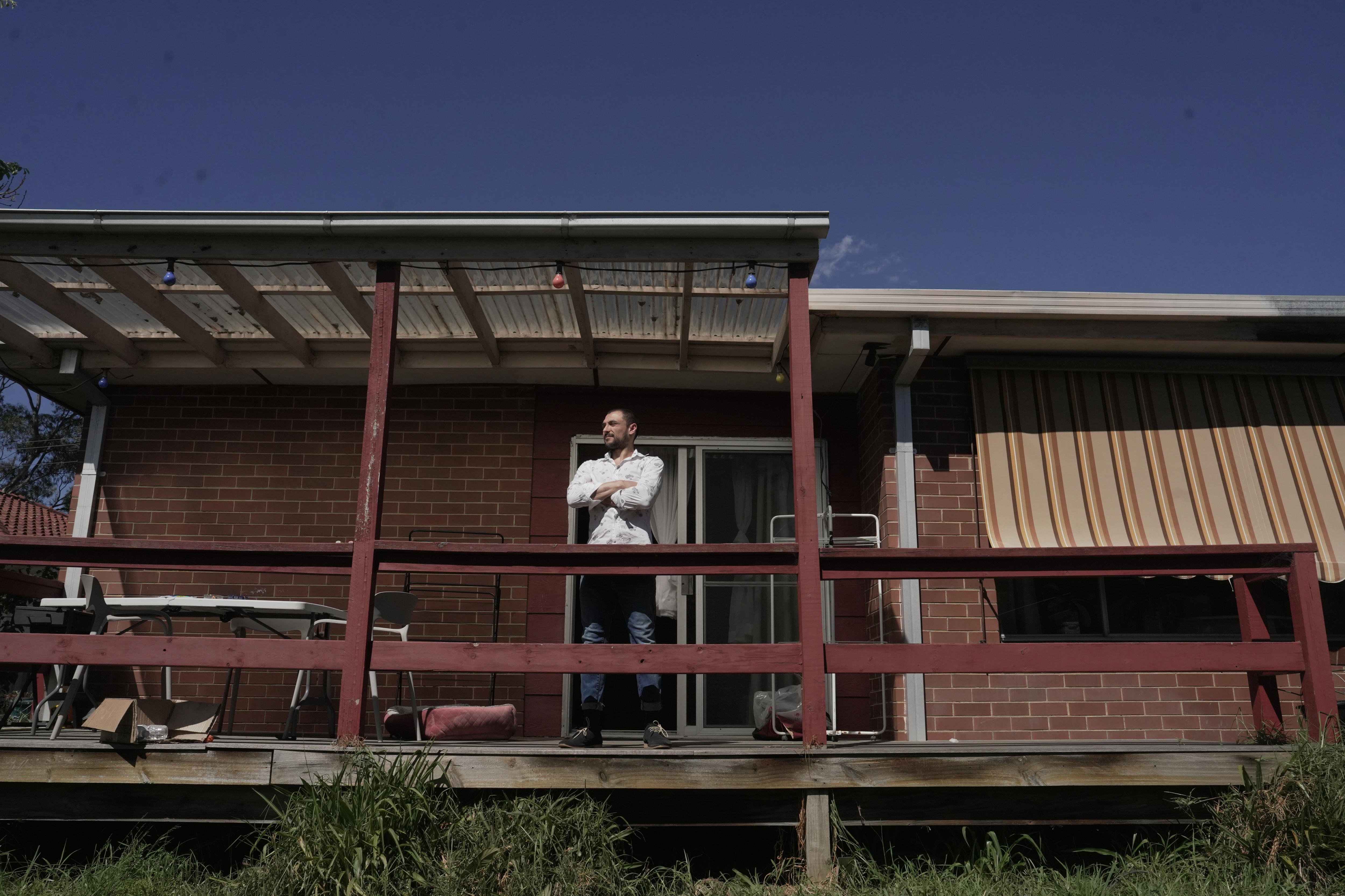 A man stands outside of his home staring out to the distance