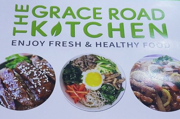 A advertisement board showing various Korean dishes and the words "The Grace Road Kitchen".