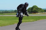 A man in a jet suit lifts off the ground.