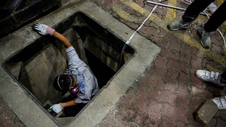 A man is climbing down a sewer manhole