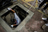 A man is climbing down a sewer manhole