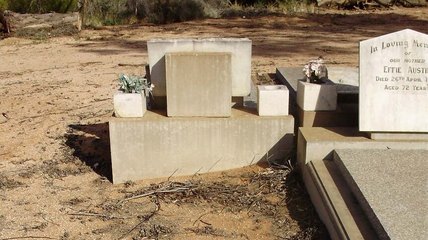 An unmarked grave in the Mallee is surrounded by red dirt and twigs.
