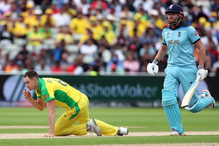 Jason Behrendorff is down on all fours looking off camera. Jonny Bairstow is about to jog past him.