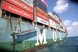 A container ship loaded up with different coloured containers.